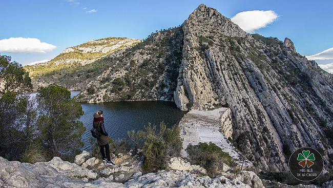 Vista de la plataforma curva de coronación de la presa con los riscos contra los que atraca